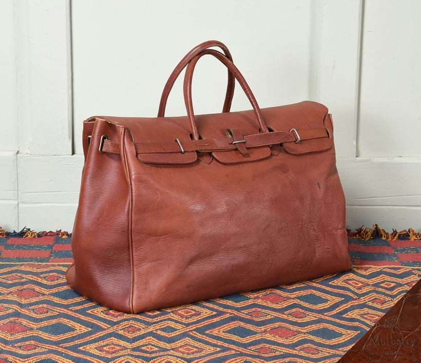 Inline Image - Lot 2: A Mulberry Chestnut  girthgrain leather holdall. The Original  designed by Roger Saul in 1975 for the Hunting, Shooting, Fishing collection– started  the ‘IT’ bag phenomena when young designer Luella Bartley asked Mulberry to have it remade and updated for her New York collection in 2002, supermodel  model Gisele Bundchen left the catwalk with it on her arm, saying ‘This is mine' | Est. £300-600 (+ fees)